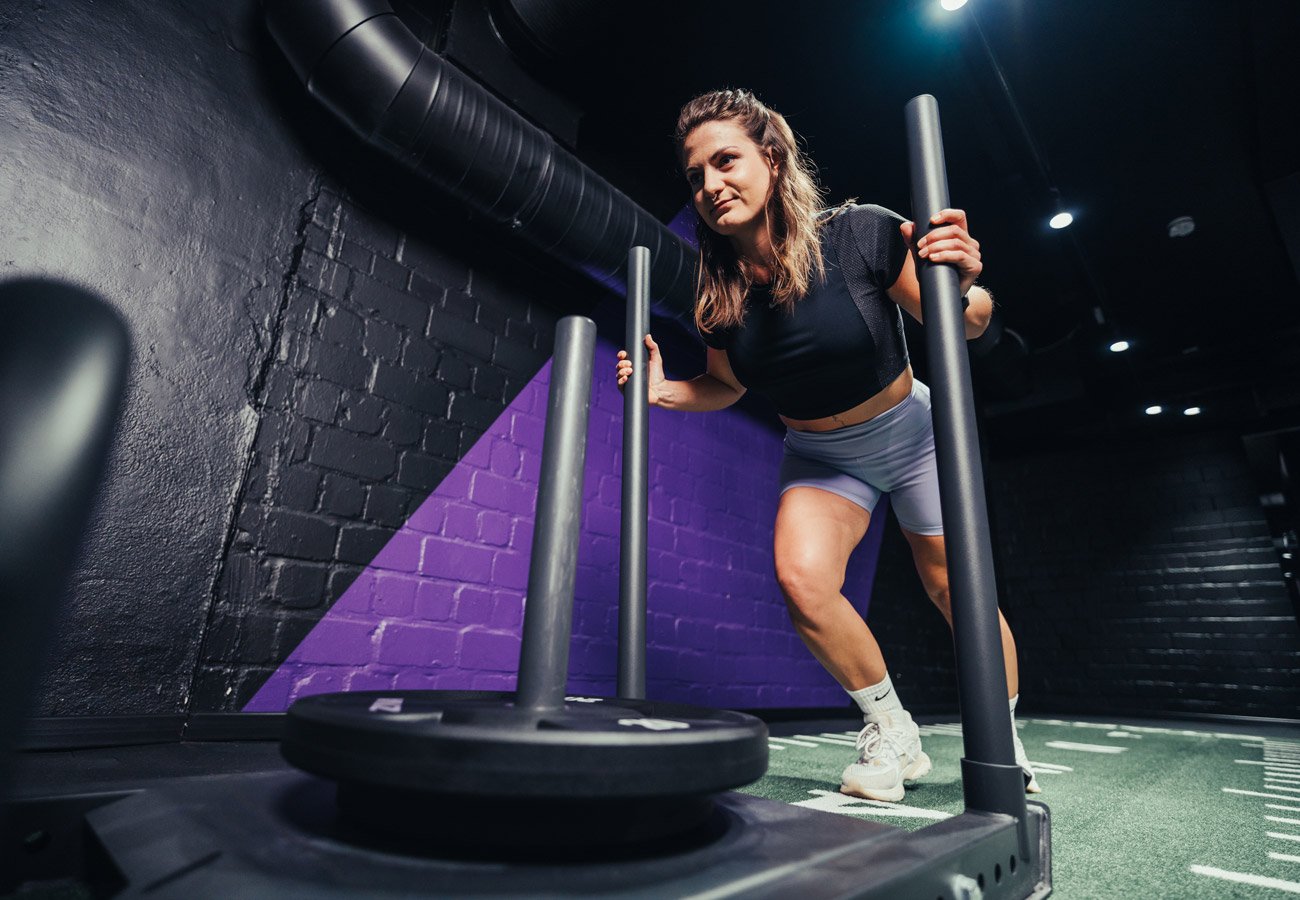 Persona empujando un trineo de entrenamiento en el área funcional del estudio FITOMAT.